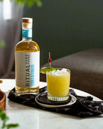 Ritual Zero Proof tequila alternative with a garnished cocktail on a table.