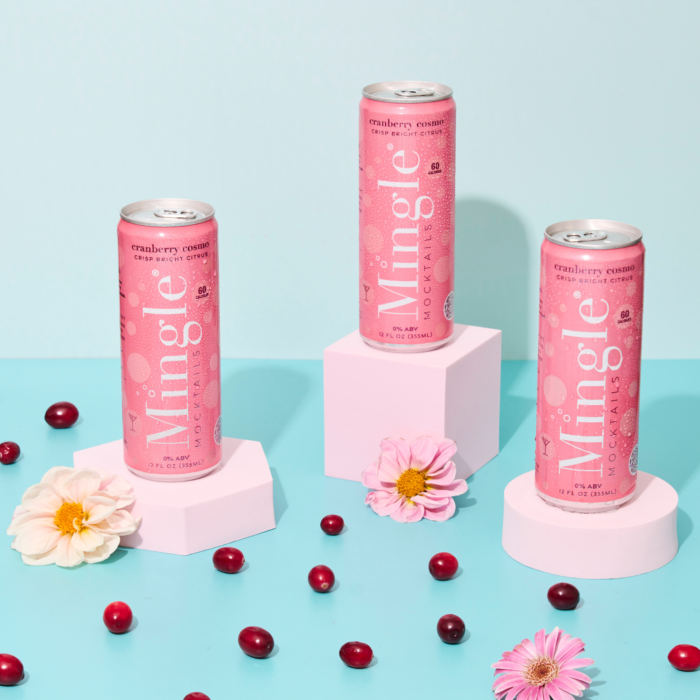 Pink Mingle Mocktails cans displayed with cranberries and flowers on pastel pink and blue background.