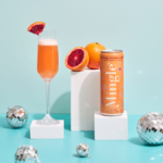 Mingle Mocktails Blood Orange flute glass garnished with orange slice, fresh oranges, and disco balls.