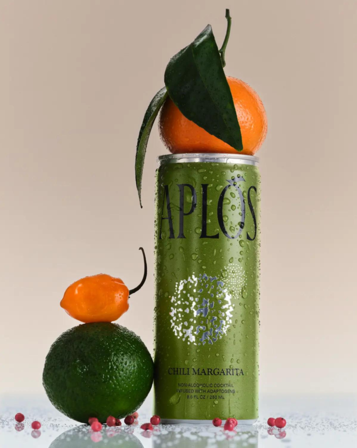 Green APLOS can with a lime, habanero pepper, and an orange with a leaf stacked on top.