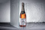 Rosé sparkling wine bottle displayed creatively with reflective and textured glass effects.