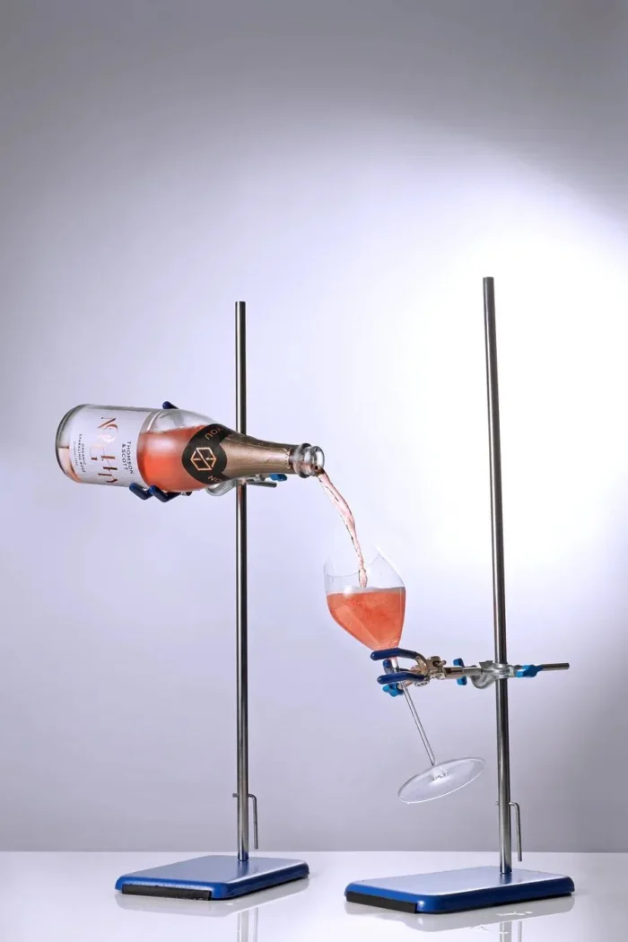 Rosé sparkling wine pouring into a glass using a scientific setup, blending elegance with innovation.