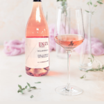 Faux Wine Melange Rosé bottle with a filled glass in an elegant setting featuring soft floral decor.