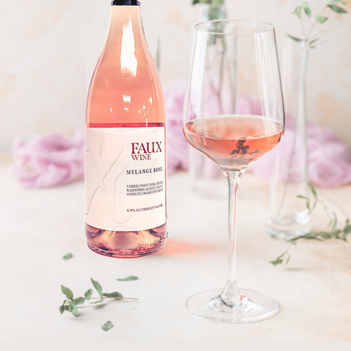 Faux Wine Melange Rosé bottle with a filled glass in an elegant setting featuring soft floral decor.